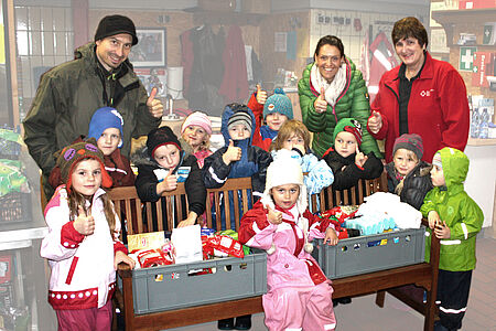 Das Fotos zeigt einige Kinder des Kindergartens mit Michael Wanger vom Elternbeirat, Maria Holzinger, Kindergartenleiterin und Heike Wessel von der Raublinger Tafel