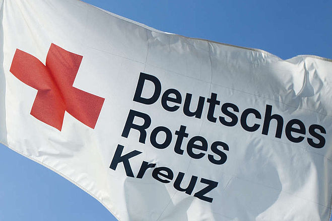 Bild zeigt wehende Fahne des Deutschen Roten Kreuzes.